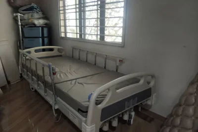 A hospital bed set up in a bedroom with the side rails fitted